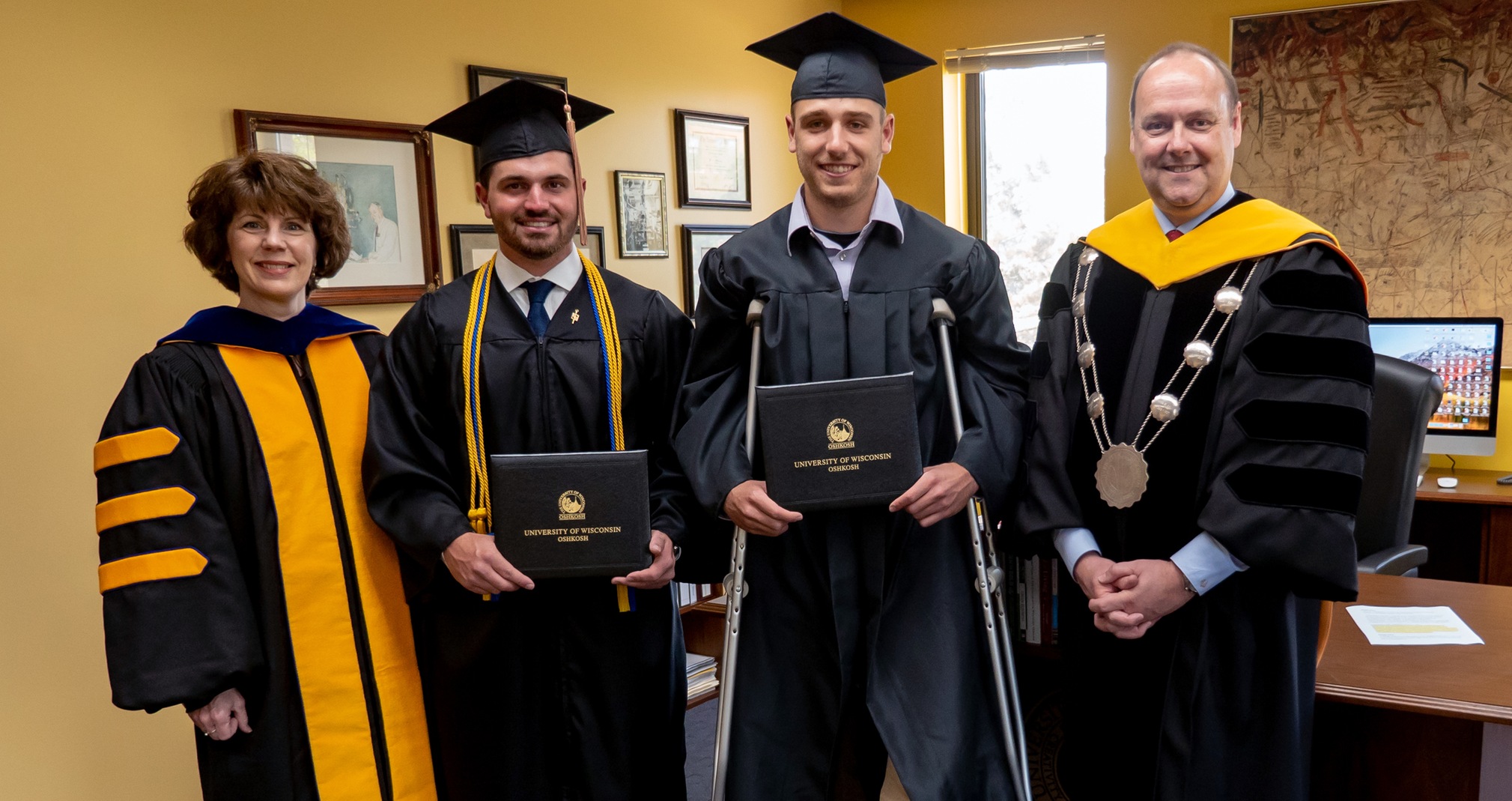 Due to a doubleheader in Illinois on May 12, baseball players Logan Reckert (middle left) and Noah Polcyn (middle right) received their diplomas on May 10 from Chancellor Andrew Leavitt (right) and College of Business Dean Barb Rau (left).