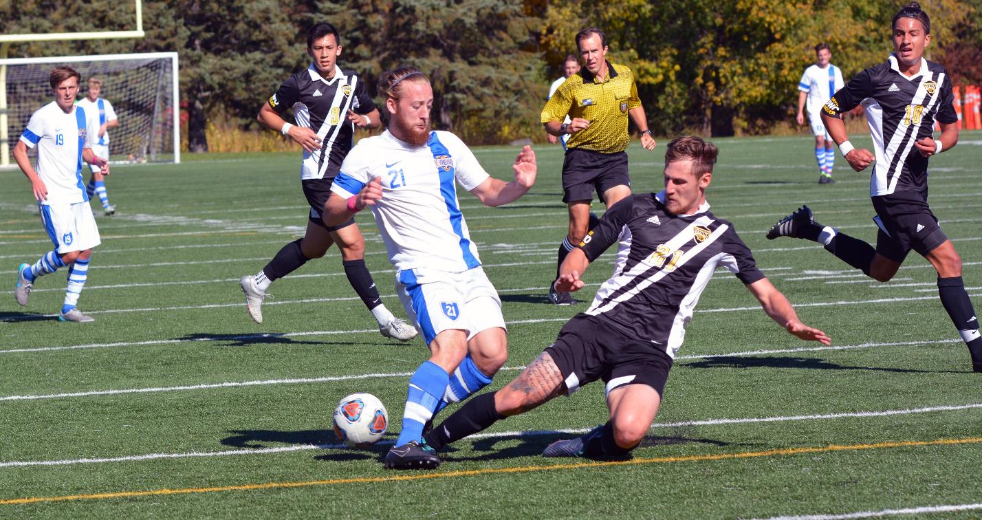 Matt Cheaney pokes the ball away to prevent a scoring opportunity by The College of St. Scholastica.