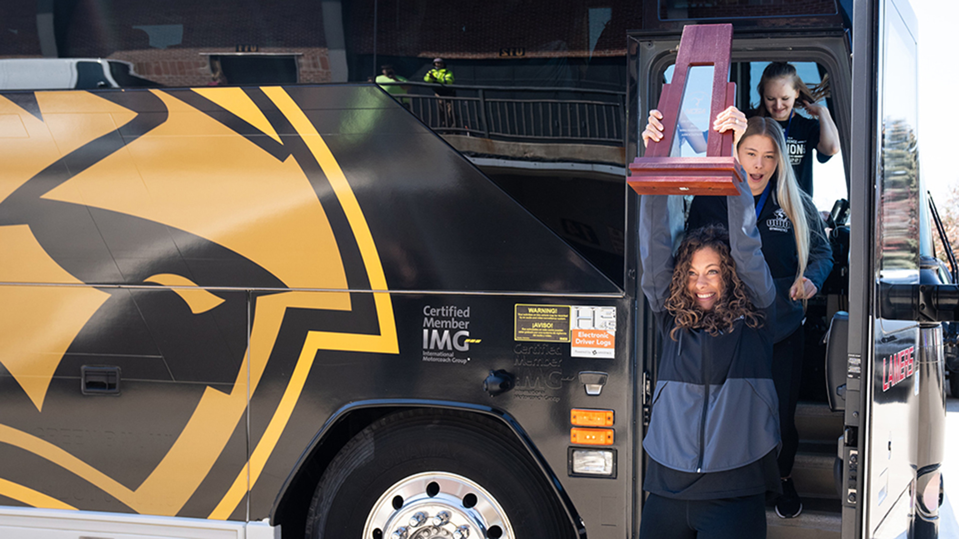 UW-Oshkosh head coach Lauren Karnitz exits the team bus at Kolf Sports Center as a national champion.