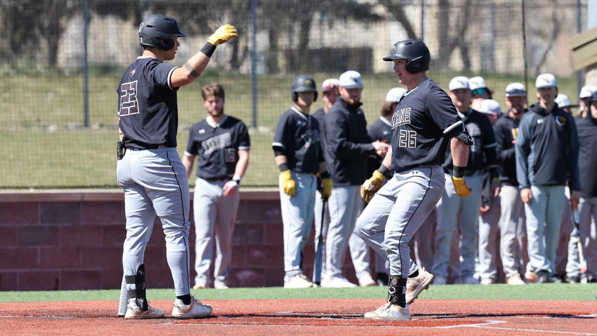Mason Kirchberg (26) celebrates with Nick Shiu (23) after scoring a run against Whitewater on Saturday. Photo Credit: Steve Frommell, UW-Oshkosh Sports Information