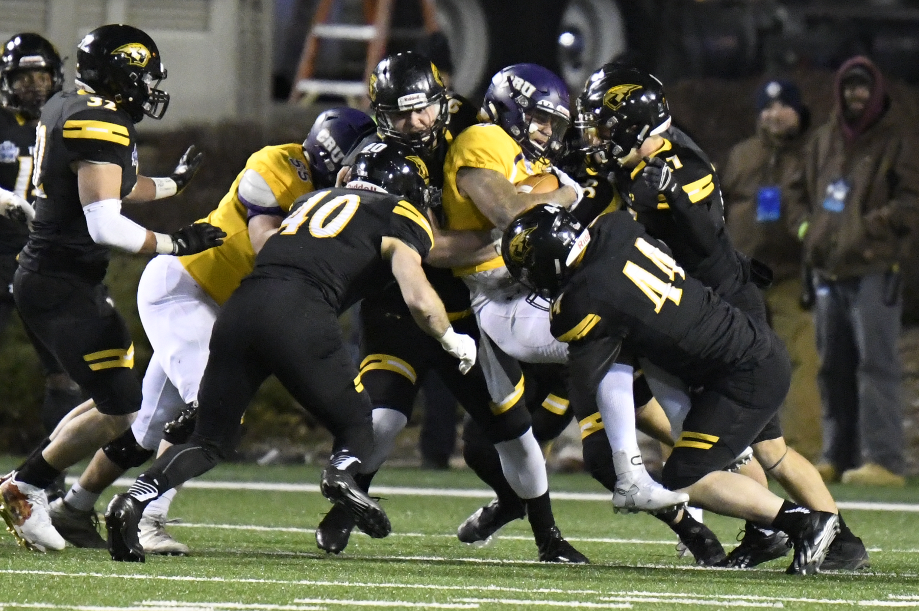 A group of Titans, including Branden Lloyd (44), AJ Plewa (7) and Jake Thein (40), stop a run by University of Mary Hardin-Baylor quarterback Blake Jackson.