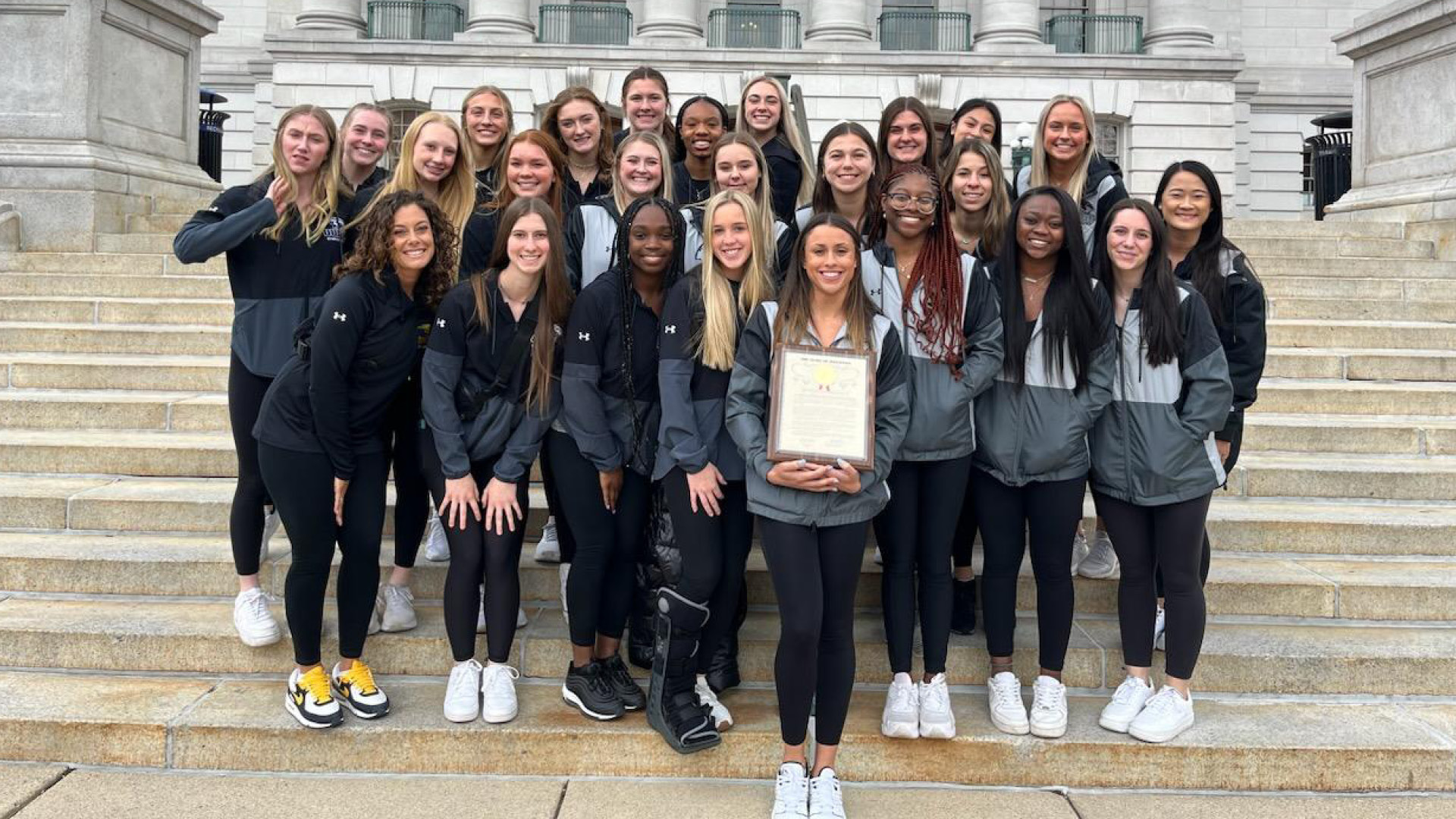 The UW-Oshkosh Women's Gymnastics Team with the plaque presented to them by the Wisconsin State Assembly